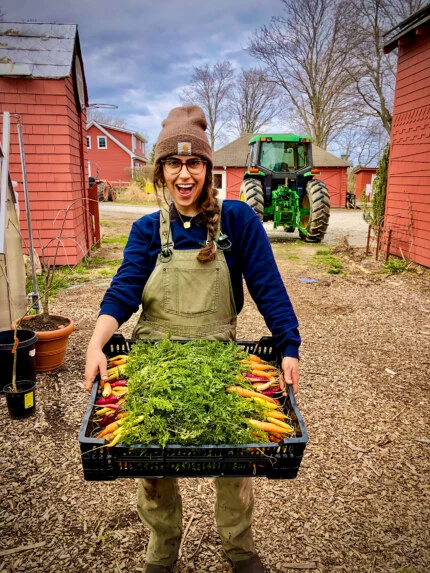 Farmer Shani Mink carrying a bin of fresh carrots