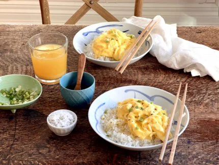 Two bowls of scrambled eggs on rice served with chopsticks